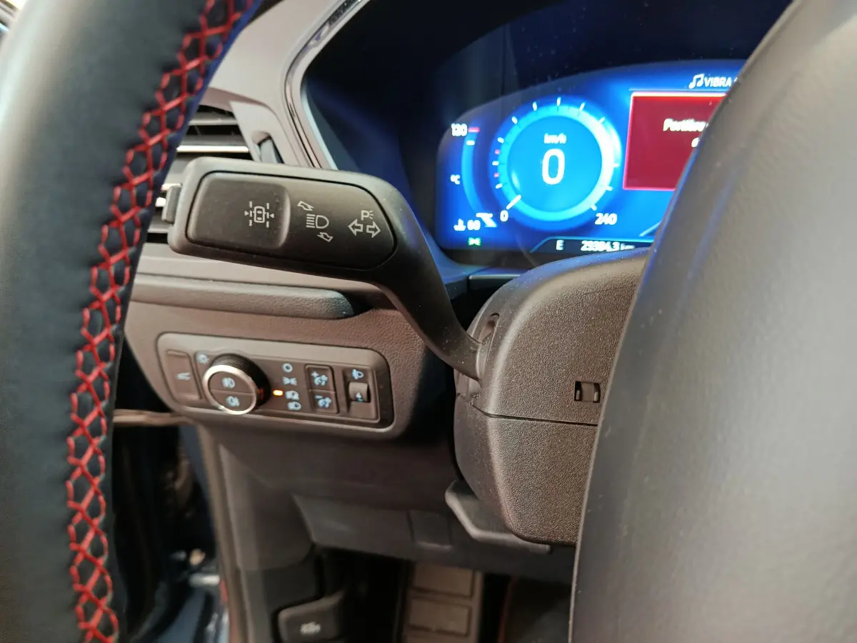 Gros plan sur le commodo gauche et le tableau de bord numérique bleu du Ford Kuga 2024, version St Line.