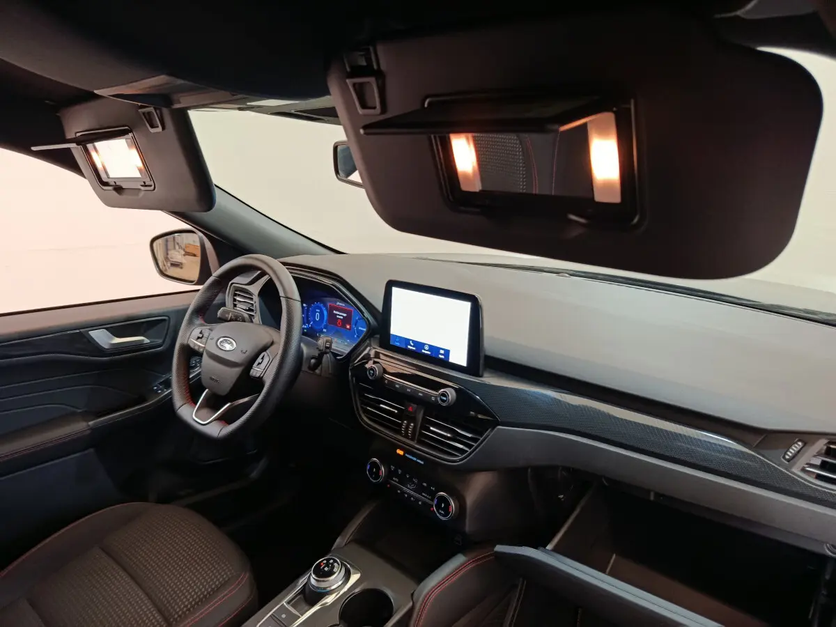Intérieur avant du Ford Kuga 2024 bleu, tableau de bord moderne avec écran tactile et volant multifonctions cuir noir.