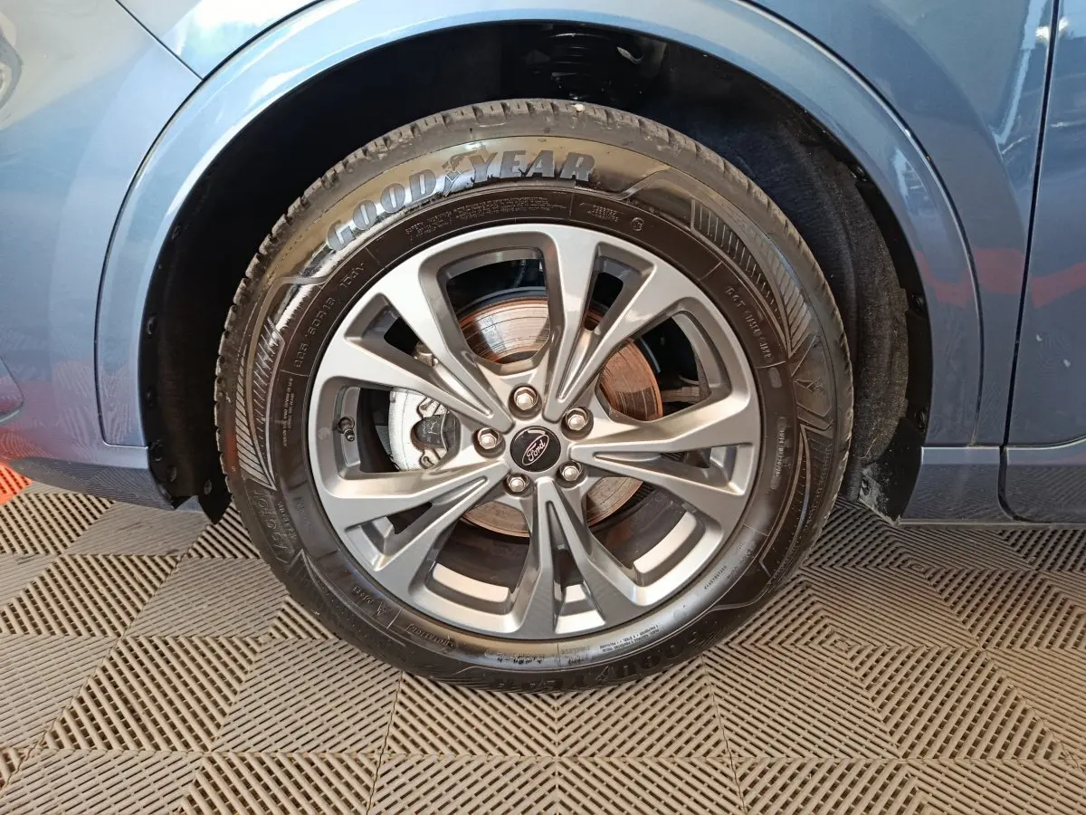 Gros plan sur la roue avant gauche du Ford Kuga bleu 2024, avec jante alliage et pneu Goodyear visible.