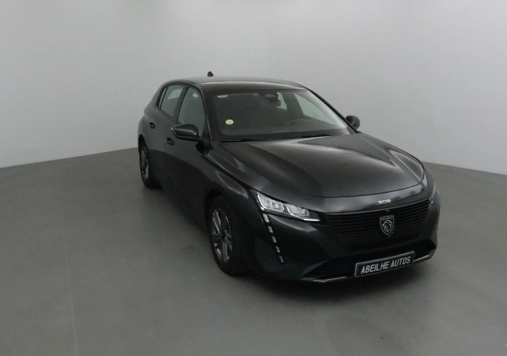 Peugeot 308 noire vue en 3/4 avant droit, mettant en valeur sa calandre moderne et ses phares LED distinctifs.