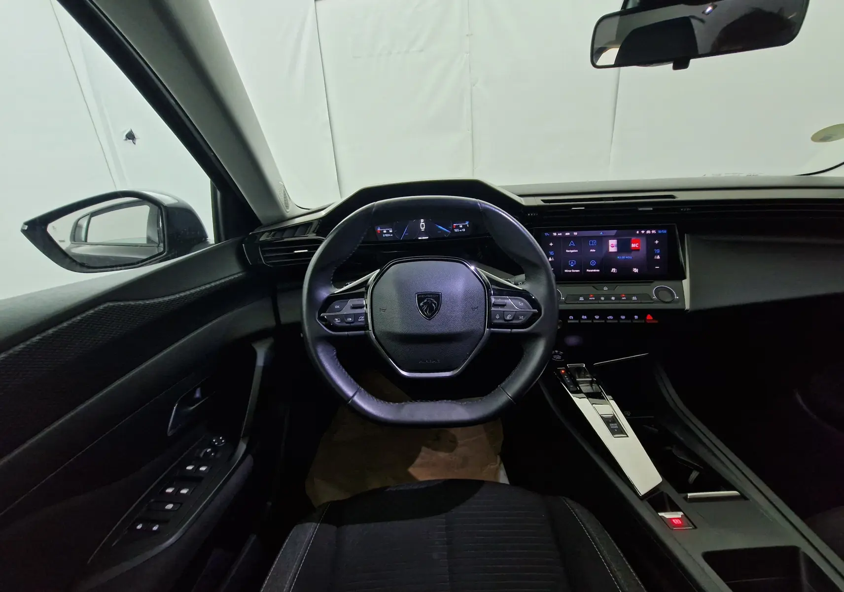 Écran tactile central de la Peugeot 308 noire 2022 affichant le menu navigation et paramètres, avec commandes climatisation.