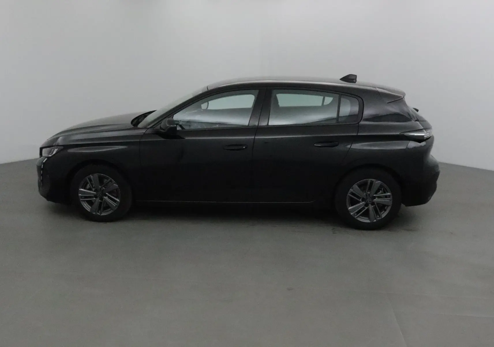 Vue arrière d'une Peugeot 308 noire 2022 avec logo lion et feux arrière étirés, stationnée en extérieur.