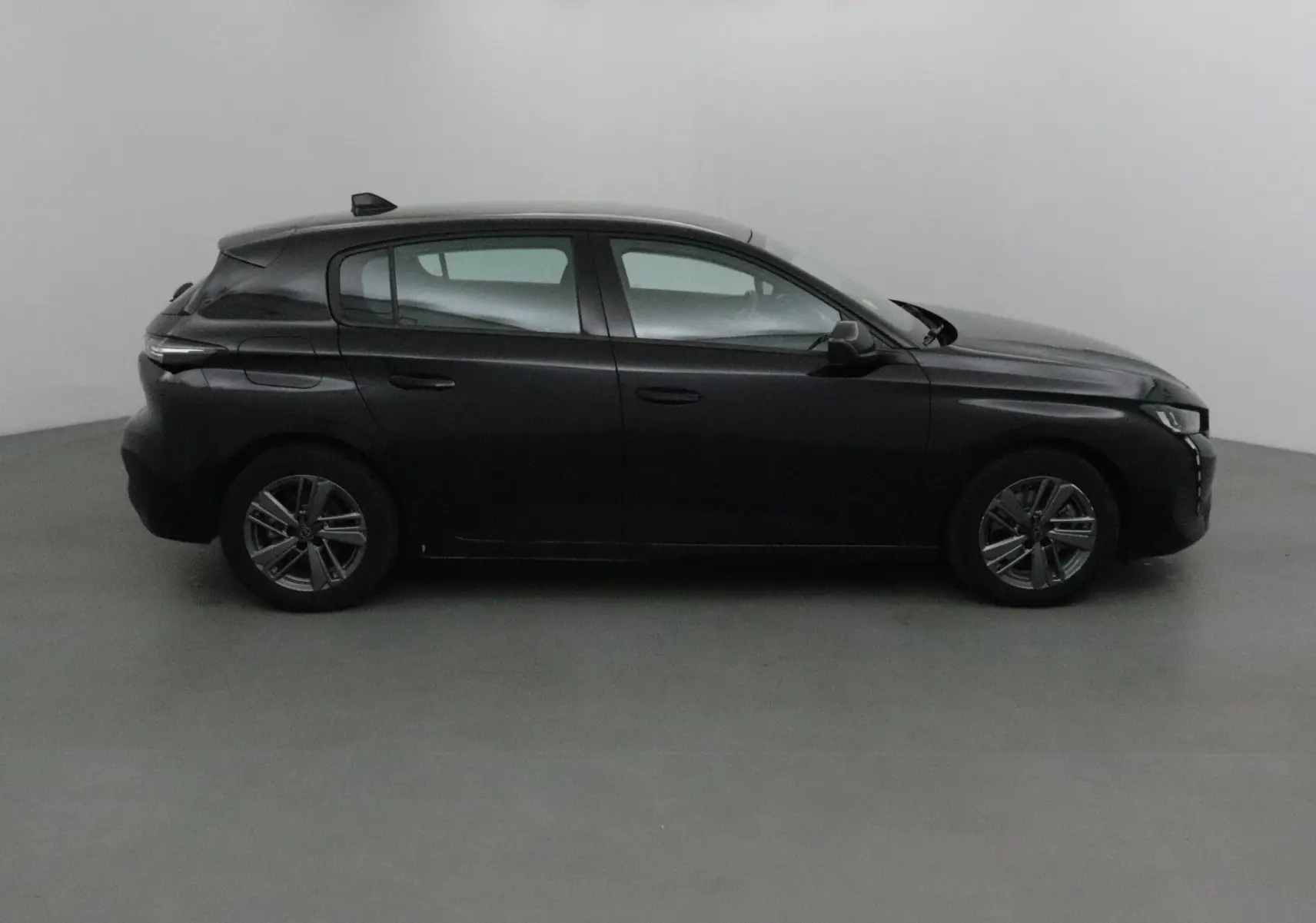 Vue intérieure du poste de conduite de la Peugeot 308 noire, avec volant cuir et tableau de bord moderne en 2022.