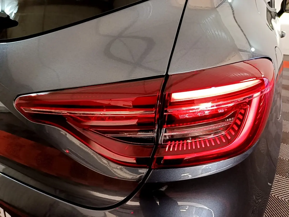 Gros plan sur le feu arrière droit rouge d'une Renault Clio Evolution gris foncé, vue de l'arrière côté droit.