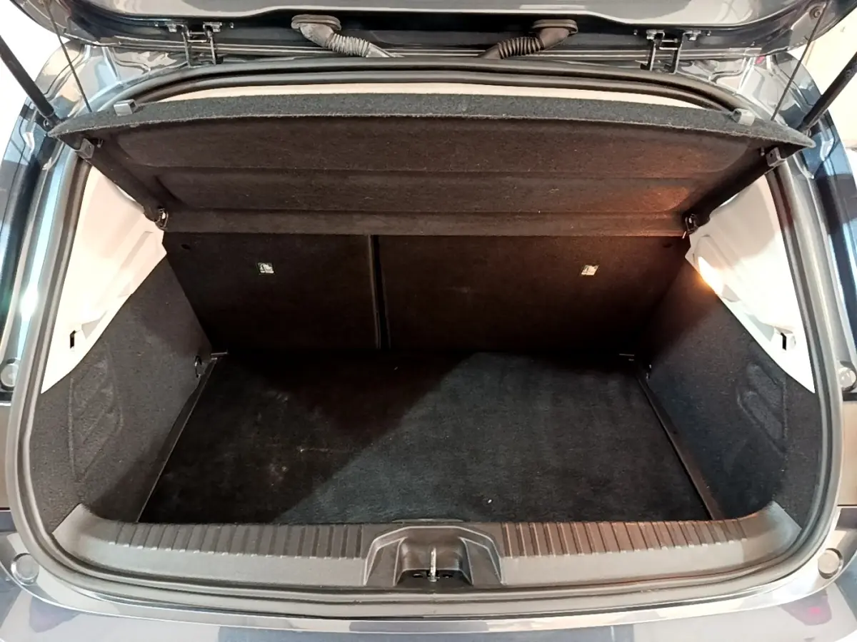 Coffre ouvert de Renault Clio gris foncé, vue arrière montrant l’espace de chargement vide et la tablette de séparation.