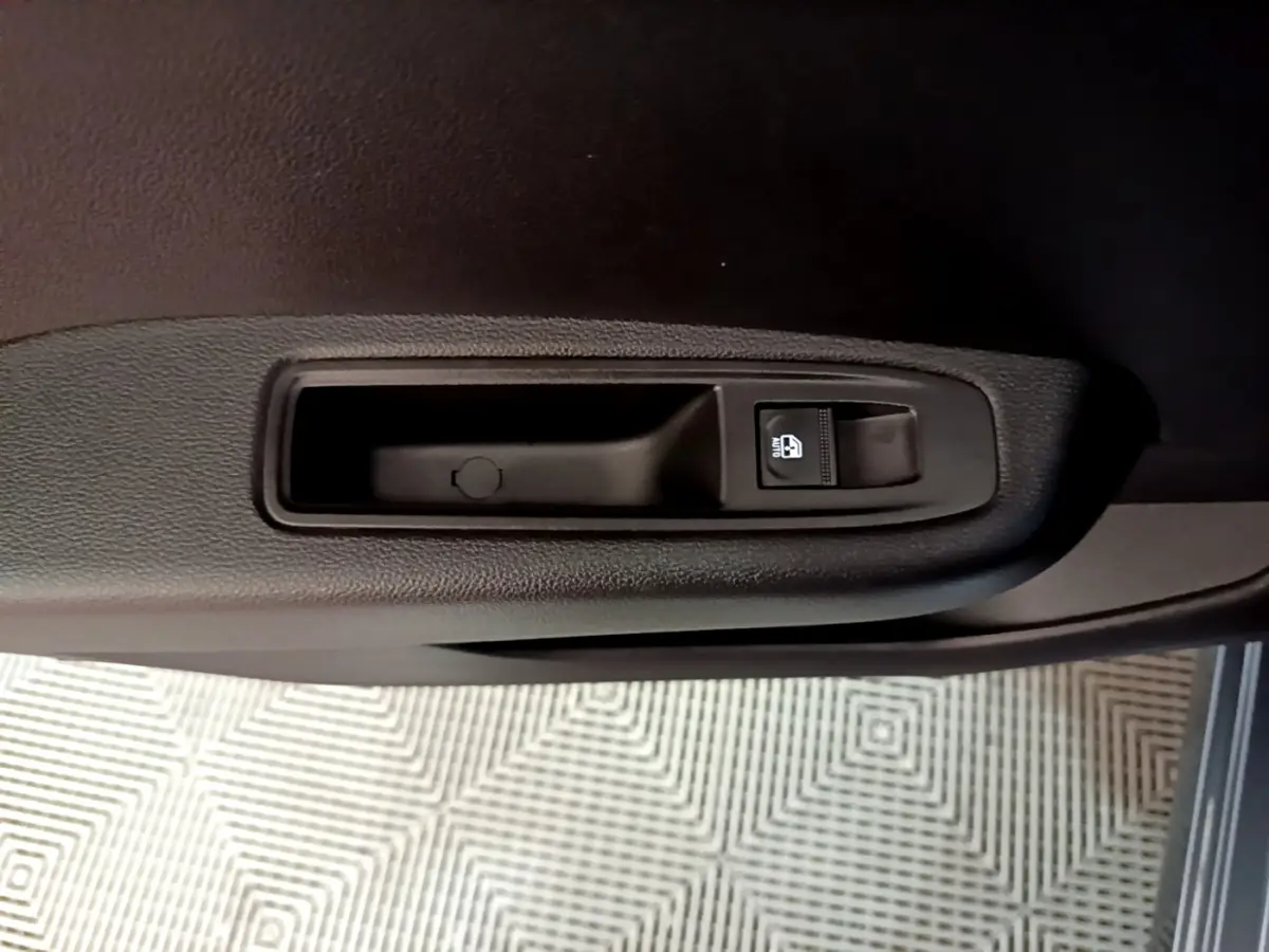 Gros plan sur la commande de lève-vitre côté conducteur de la Renault Clio gris foncé Evolution SCe 65 2022.