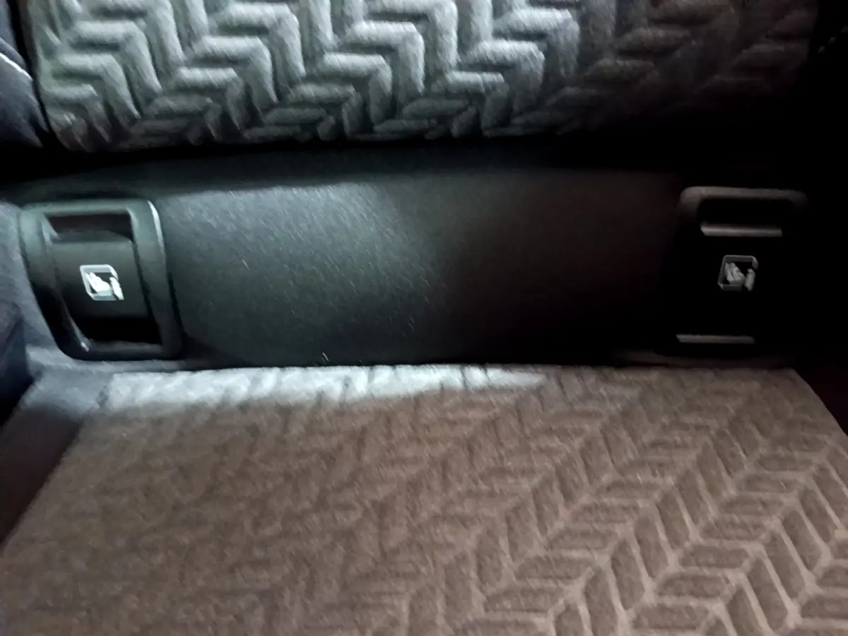 Gros plan sur la banquette arrière grise à motif chevrons de la Renault Clio Evolution SCe 65, avec boutons de rabattement.