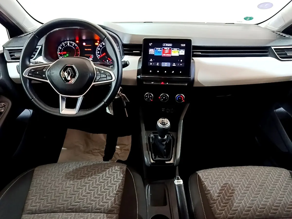 Vue intérieure avant de la Renault Clio gris foncé 2022, volant cuir, tableau de bord avec écran tactile central et boîte manuelle.