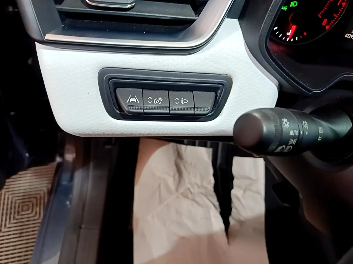 Gros plan sur les commandes d'aide à la conduite et réglages lumineux du tableau de bord blanc de la Renault Clio gris foncé.