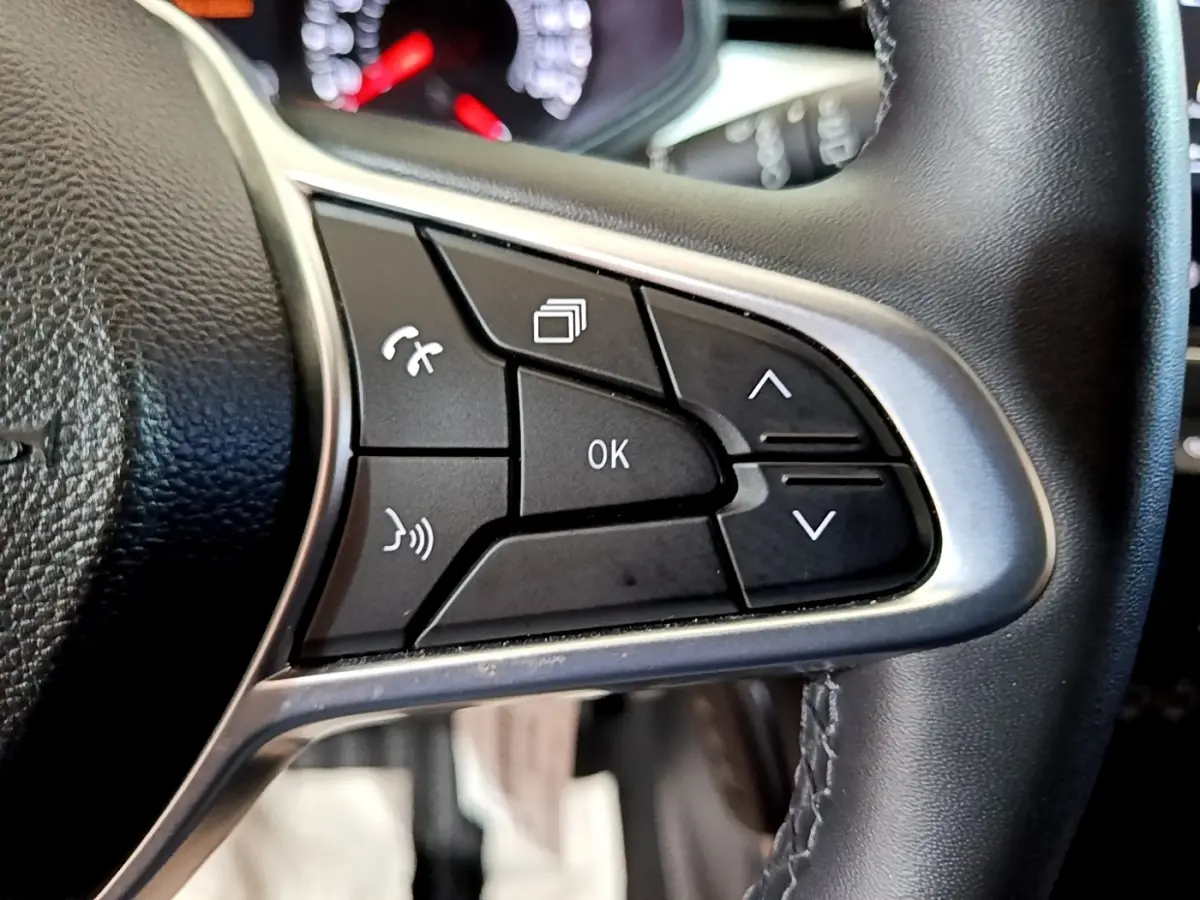 Gros plan sur les commandes multifonctions à droite du volant cuir noir de la Renault Clio gris foncé 2022.