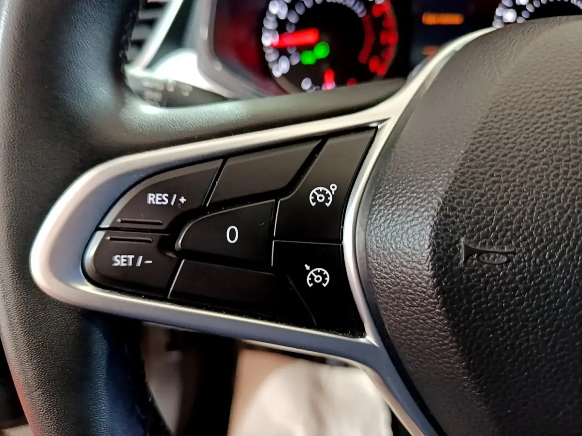 Gros plan sur les commandes de régulateur de vitesse au volant cuir noir de la Renault Clio gris foncé 2022.