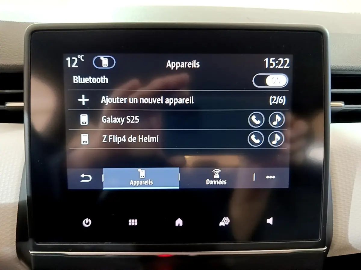 Écran tactile central de la Renault Clio gris foncé, affichant la connexion Bluetooth avec appareils listés.
