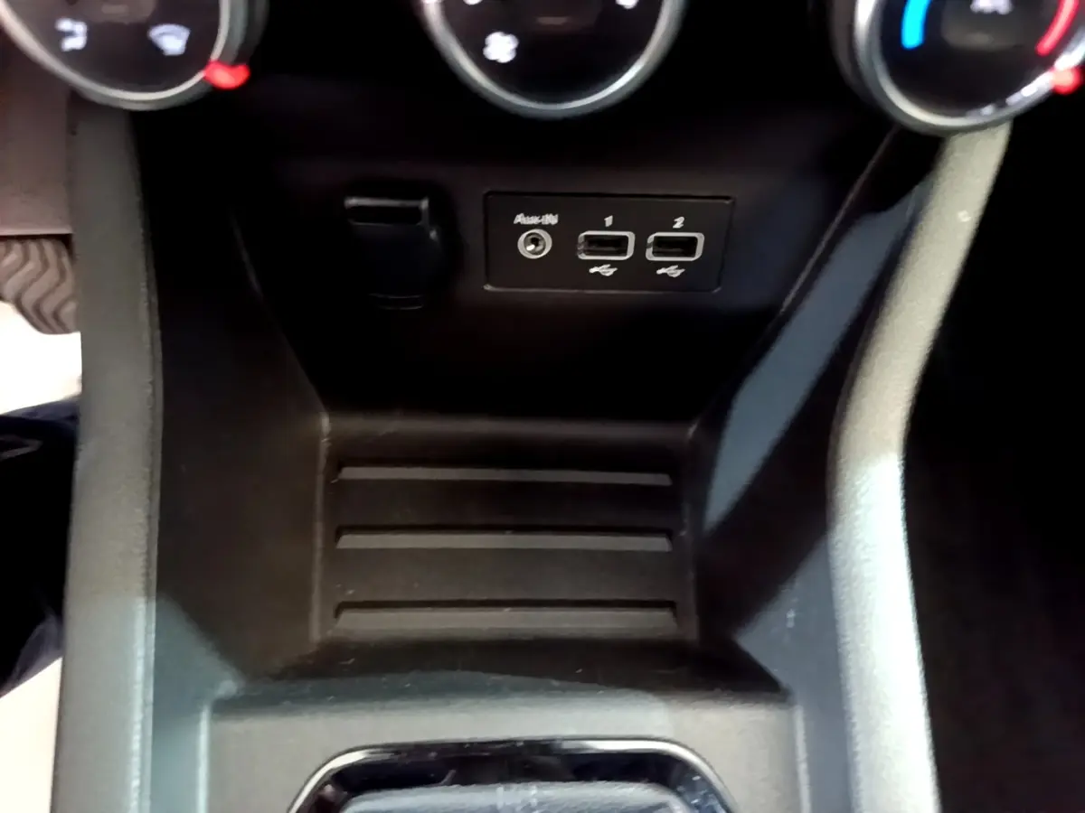 Gros plan sur la console centrale noire de la Renault Clio Evolution SCe 65, avec ports USB et prise auxiliaire visibles.