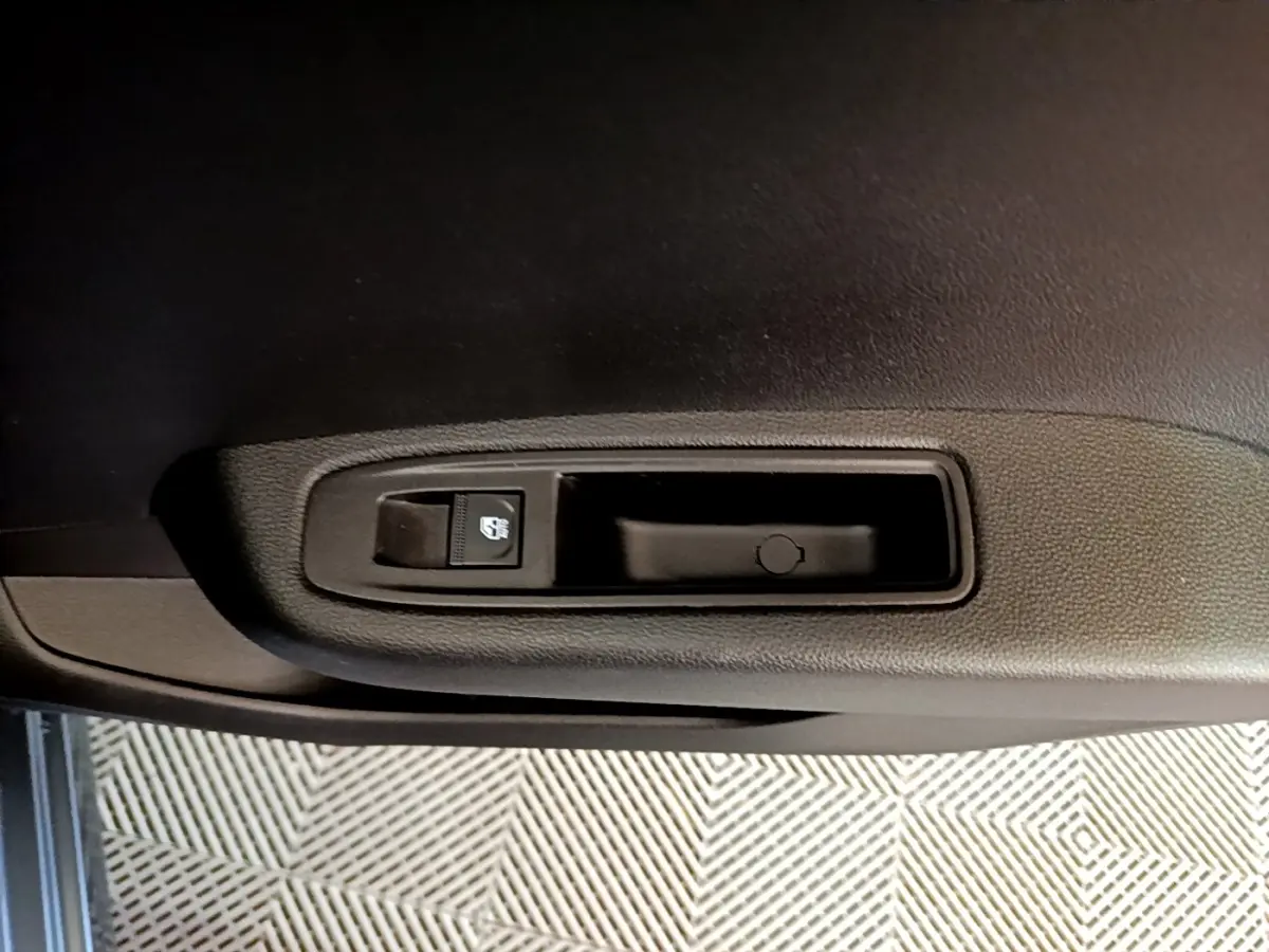 Gros plan sur la commande de lève-vitre électrique côté conducteur de la Renault Clio gris foncé Evolution SCe 65 2022.