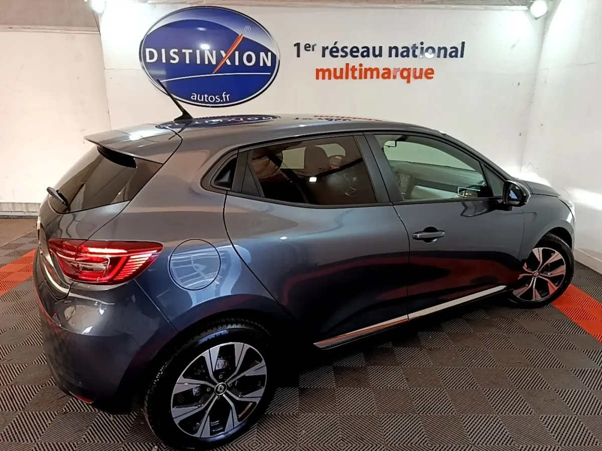 Vue 3/4 arrière droite d'une Renault Clio Evolution SCe 65 gris foncé avec jantes alliage et feux arrière LED allumés.