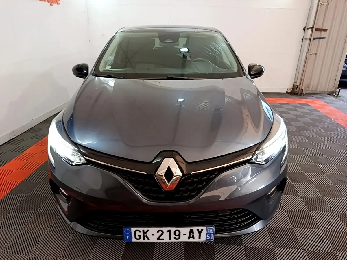 Renault Clio Evolution SCe 65 gris foncé vue de face avec phares LED allumés dans un garage.