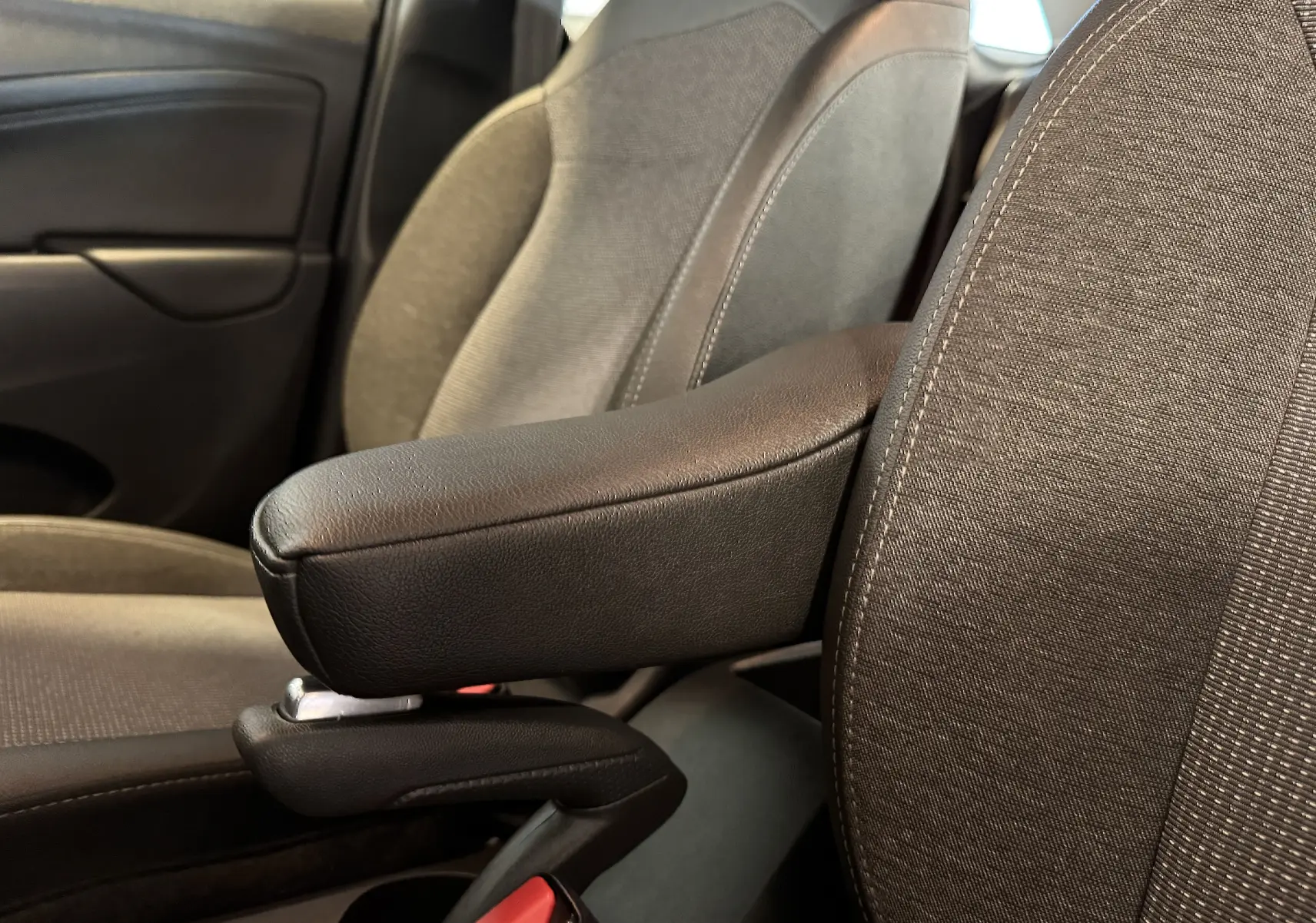 Accoudoir central en cuir noir entre les sièges avant gris foncé de l’Opel Crossland rouge, vue intérieure côté droit.