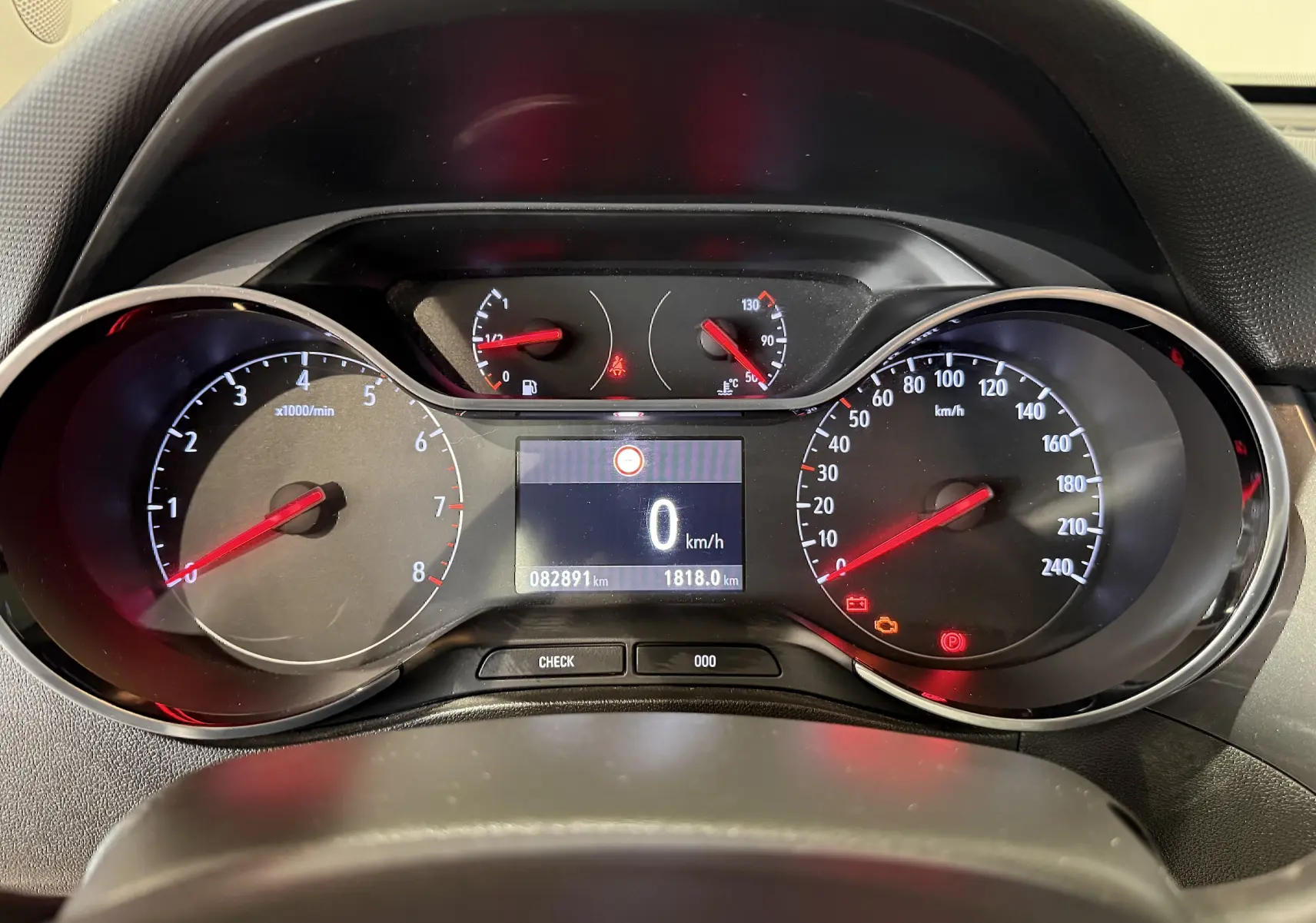 Vue rapprochée du tableau de bord de l'Opel Crossland rouge, affichant le compteur de vitesse et le compte-tours à l'arrêt.