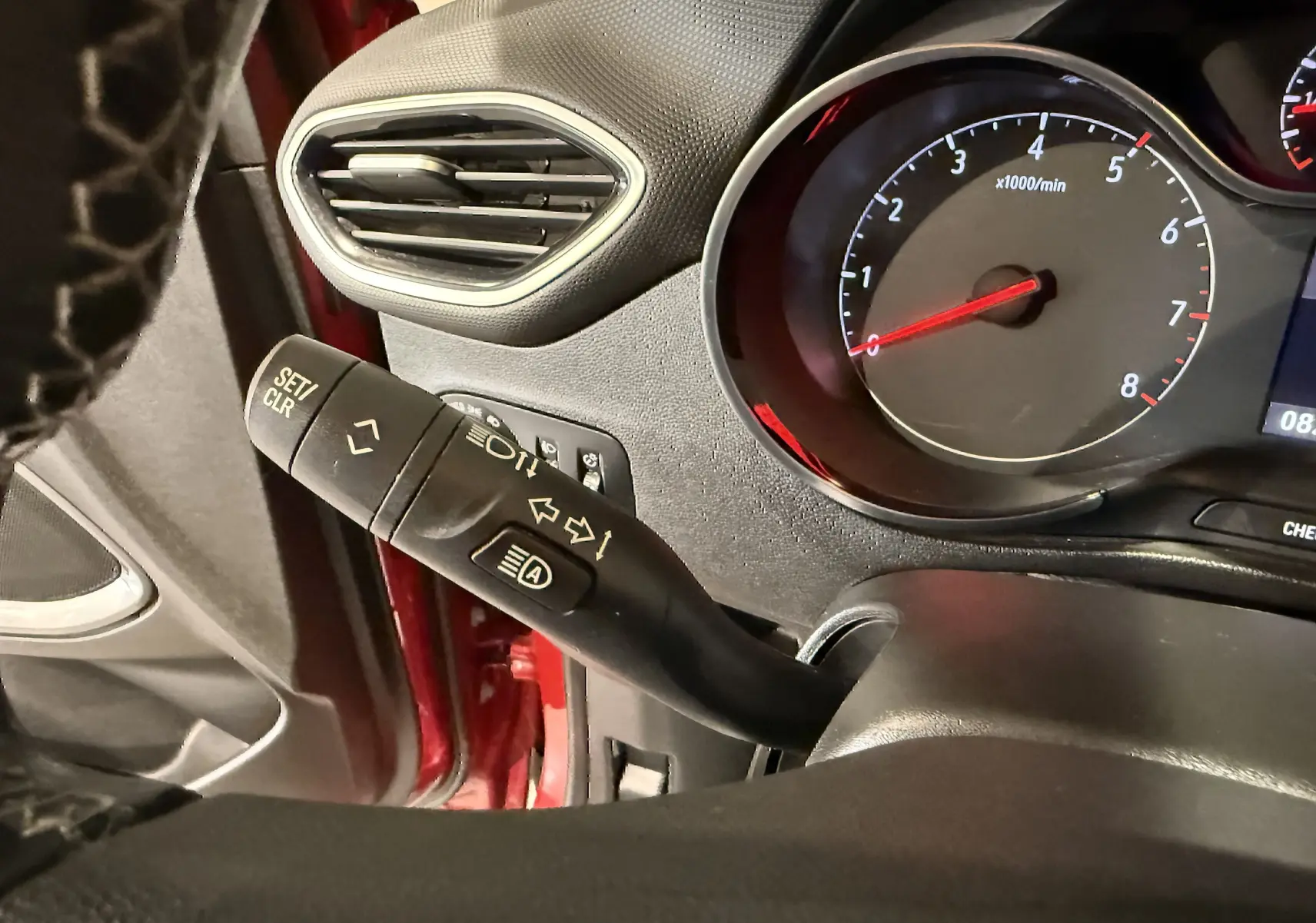 Détail du commodo gauche et tableau de bord noir de l’Opel Crossland rouge, version 2022 essence, vue intérieure côté conducteur.