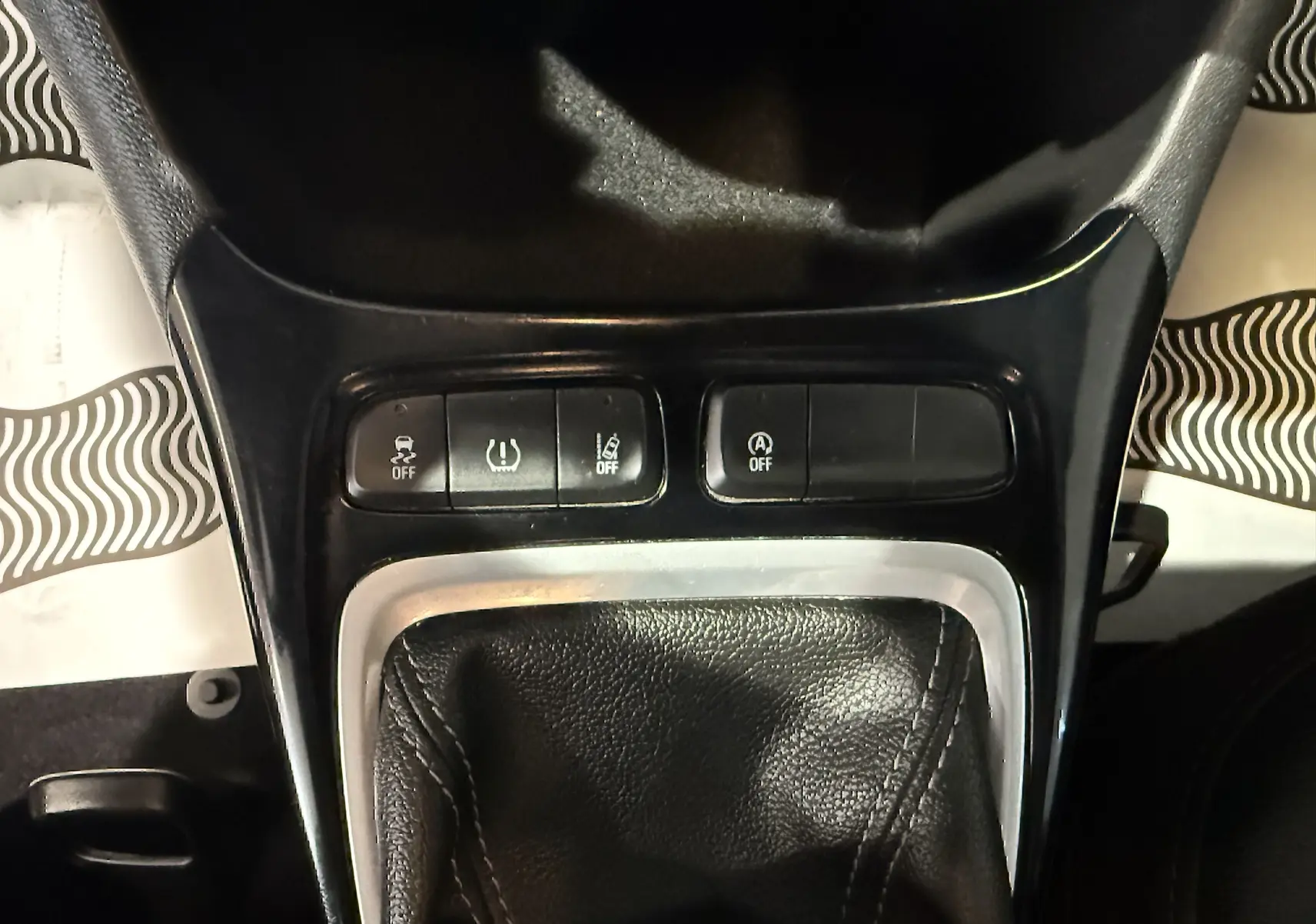 Gros plan sur la console centrale noire de l'Opel Crossland rouge, montrant les boutons de contrôle et le soufflet de levier de vitesse.