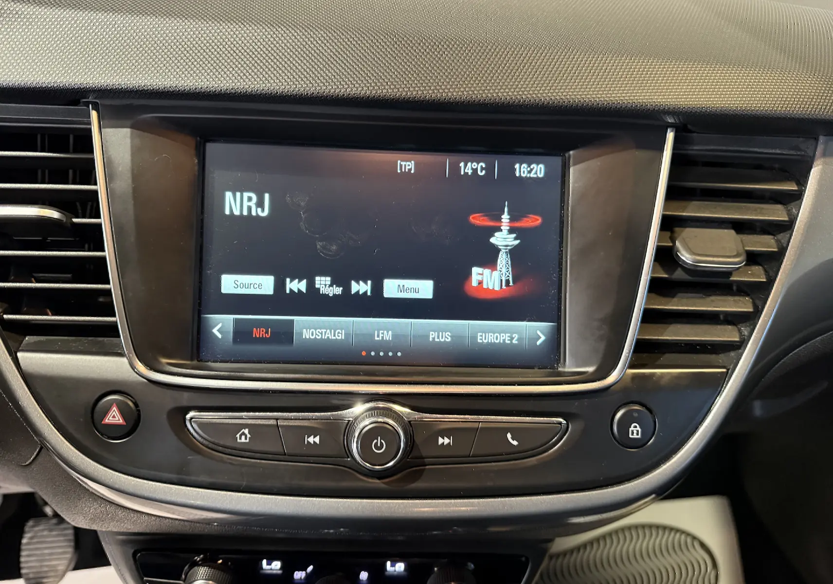 Gros plan sur l’écran multimédia central de l’Opel Crossland 2022 affichant la radio NRJ, entouré de commandes et grilles d’aération noires.