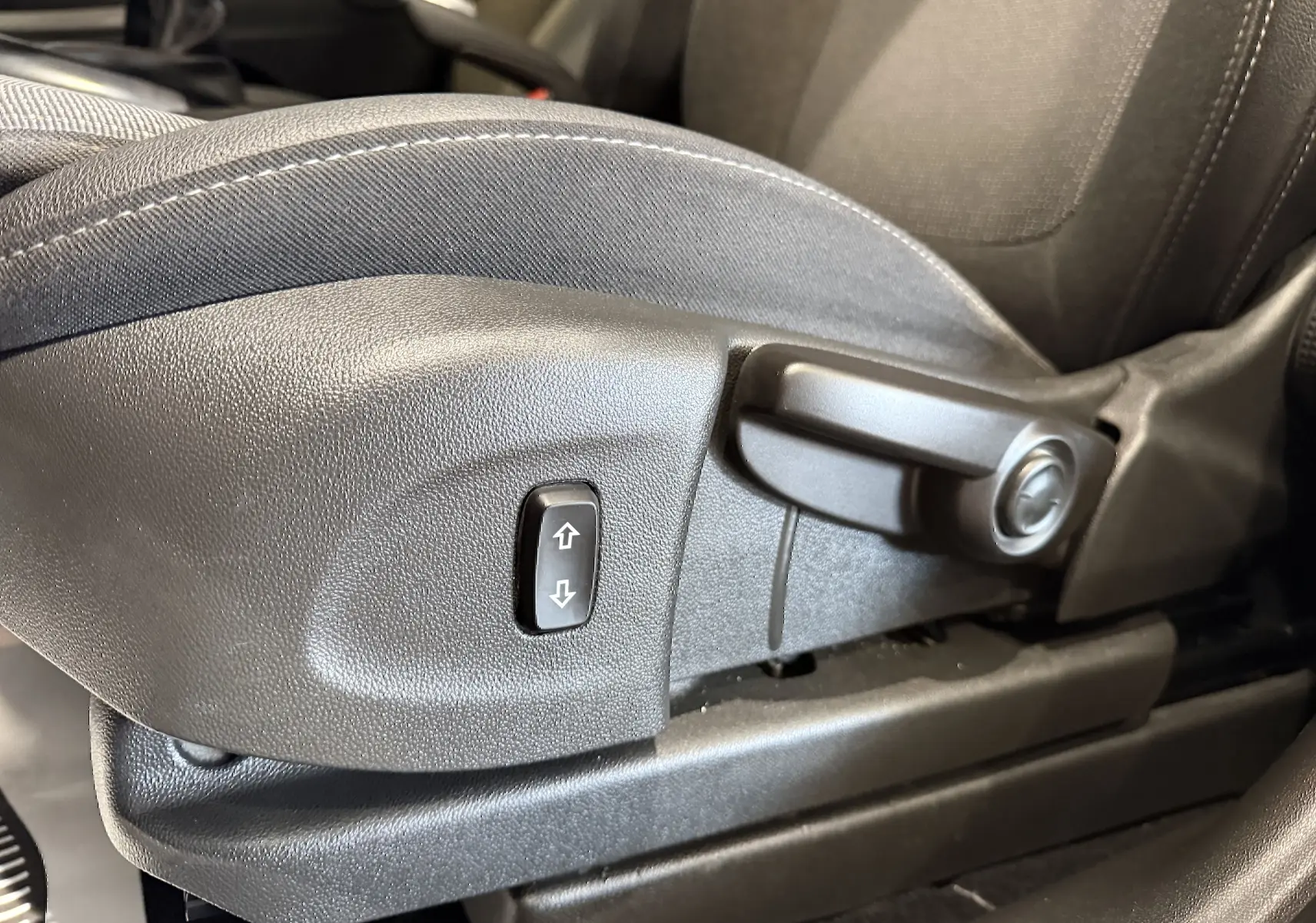 Gros plan sur la commande de réglage manuel du siège avant en tissu gris de l’Opel Crossland 2022.