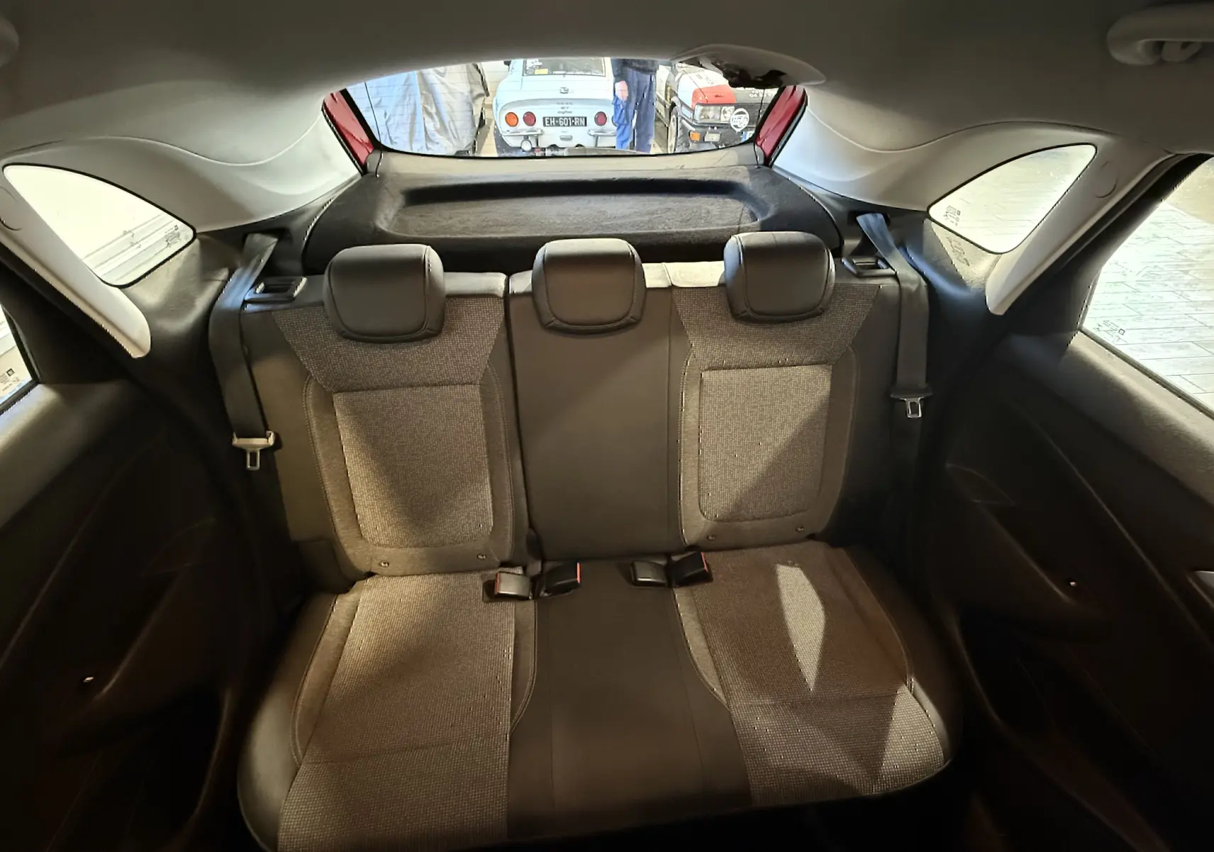 Vue intérieure arrière montrant la banquette arrière grise de l’Opel Crossland 2022, avec trois appuie-têtes et ceintures de sécurité.