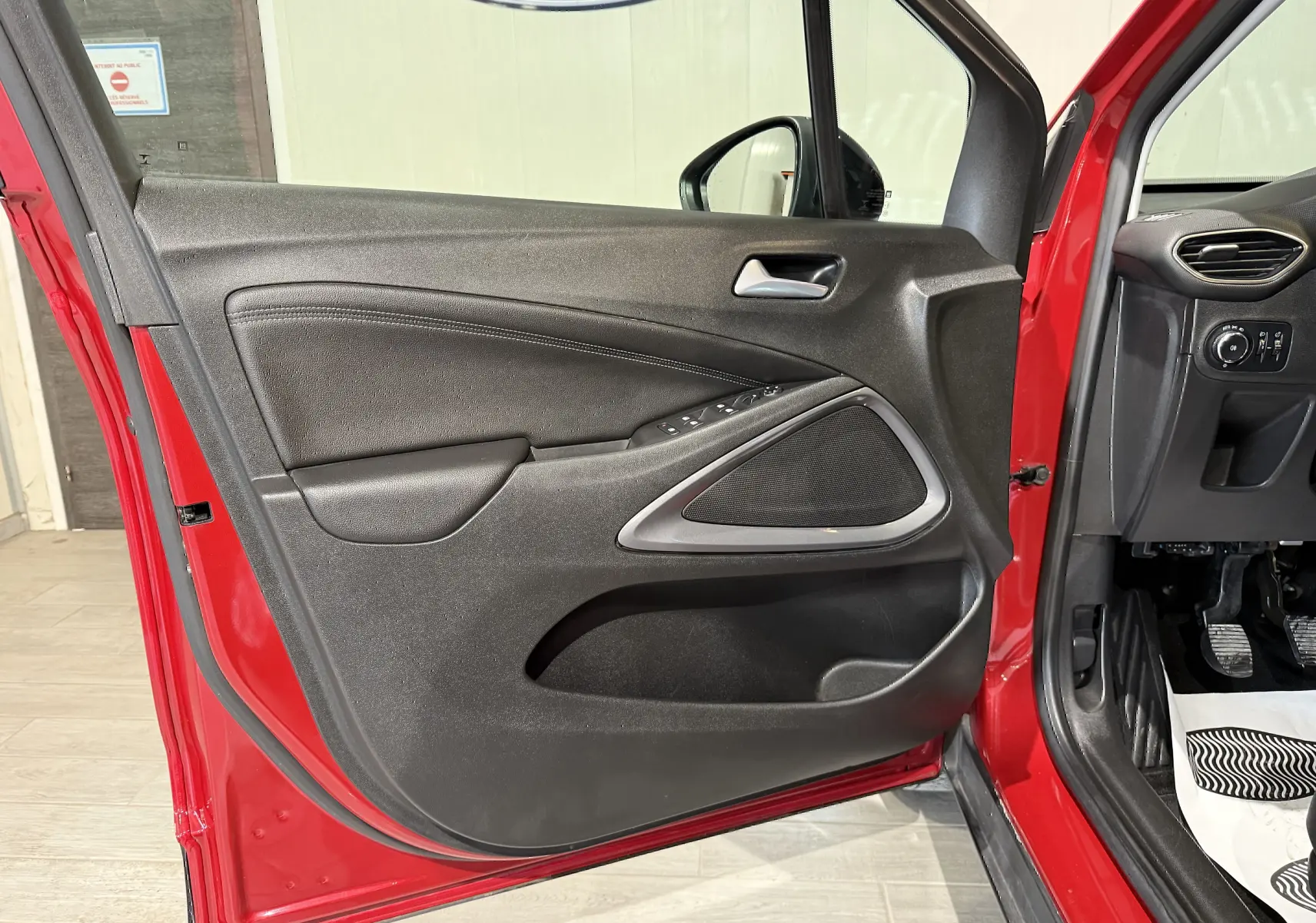 Vue intérieure de la porte avant gauche rouge de l’Opel Crossland 2022, avec commandes électriques et haut-parleur intégré.