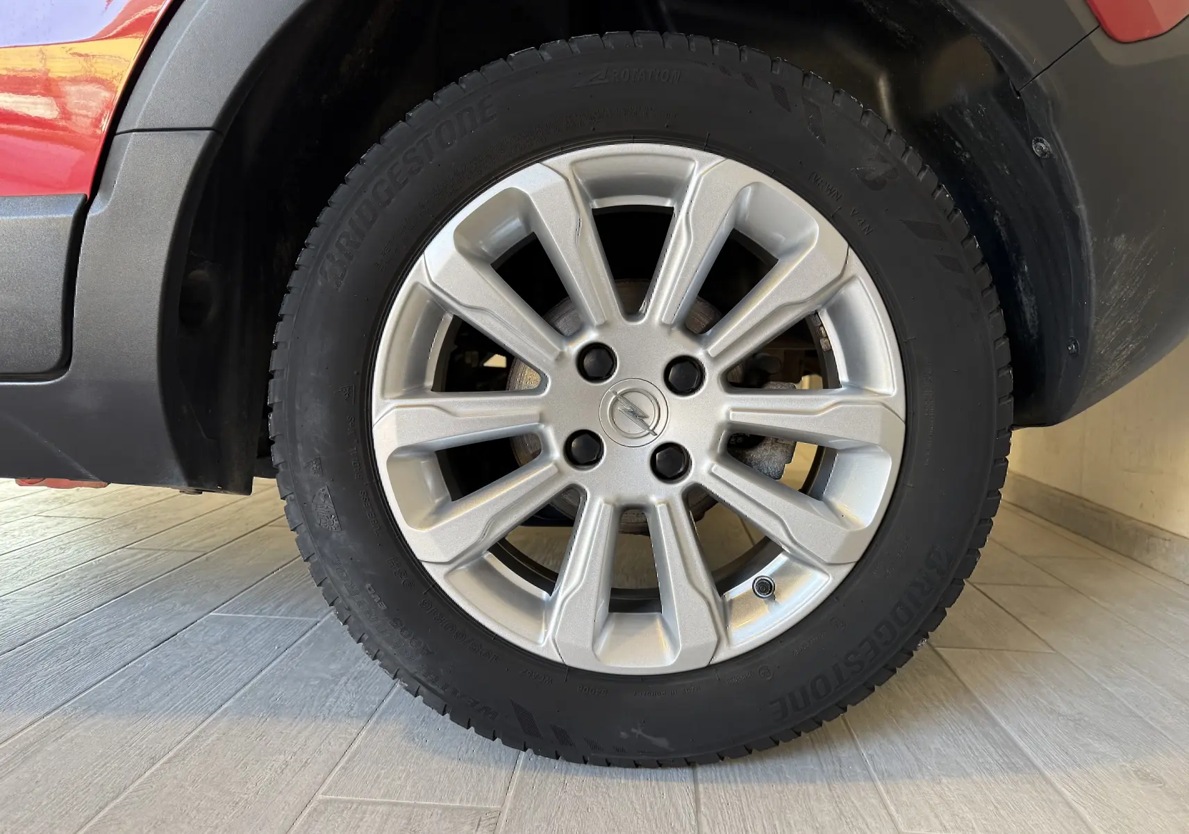 Gros plan sur la roue avant droite de l’Opel Crossland rouge 2022, mettant en valeur la jante alliage et le pneu Bridgestone.