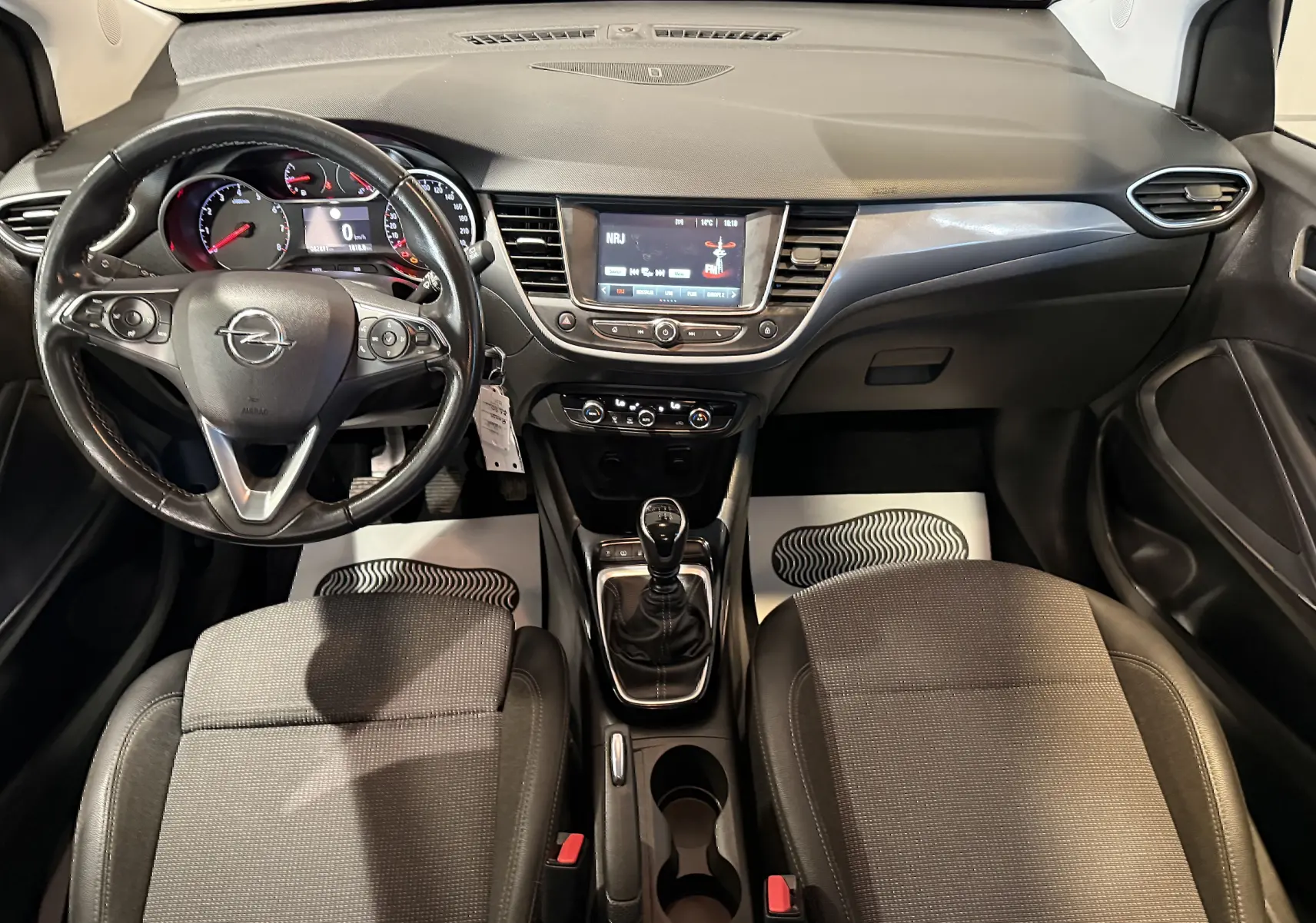 Vue intérieure frontale de l’Opel Crossland 2022, tableau de bord noir avec volant multifonction et boîte manuelle.
