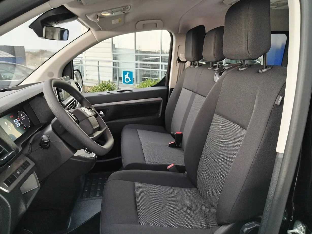 Vue intérieure côté conducteur du Fiat Ulysse 2026, sièges tissu gris foncé avec tableau de bord moderne.