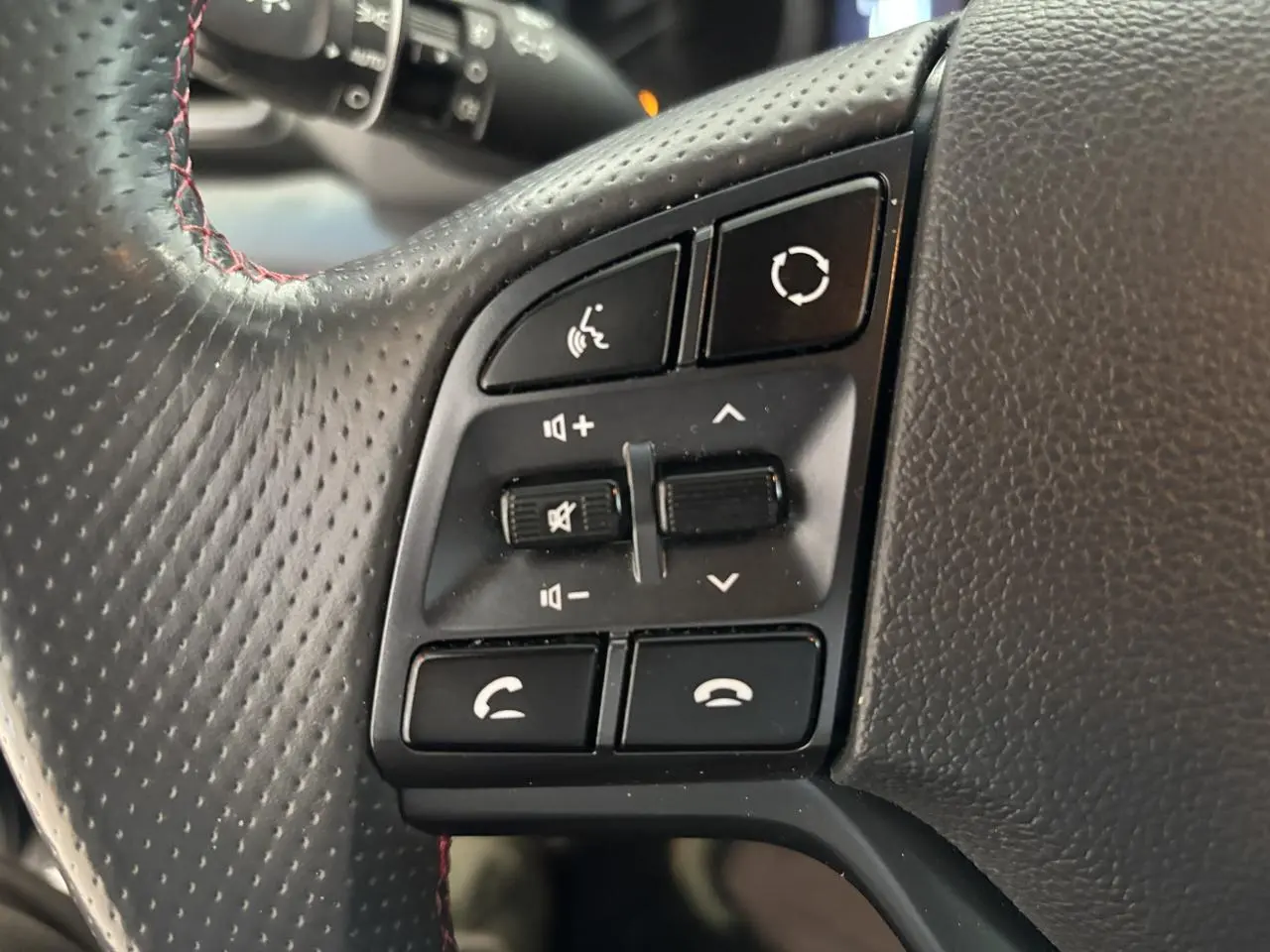 Gros plan sur les commandes gauche du volant cuir noir perforé avec surpiqûres rouges du Hyundai Tucson N Line 2020.
