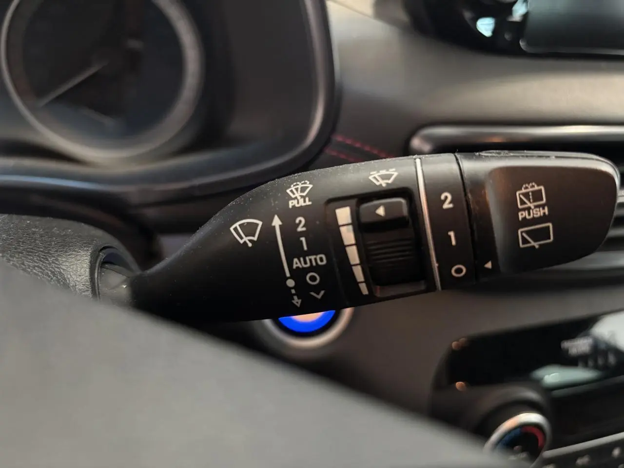 Gros plan sur la commande des essuie-glaces du Hyundai Tucson noir, avec détails des symboles blancs sur levier noir.