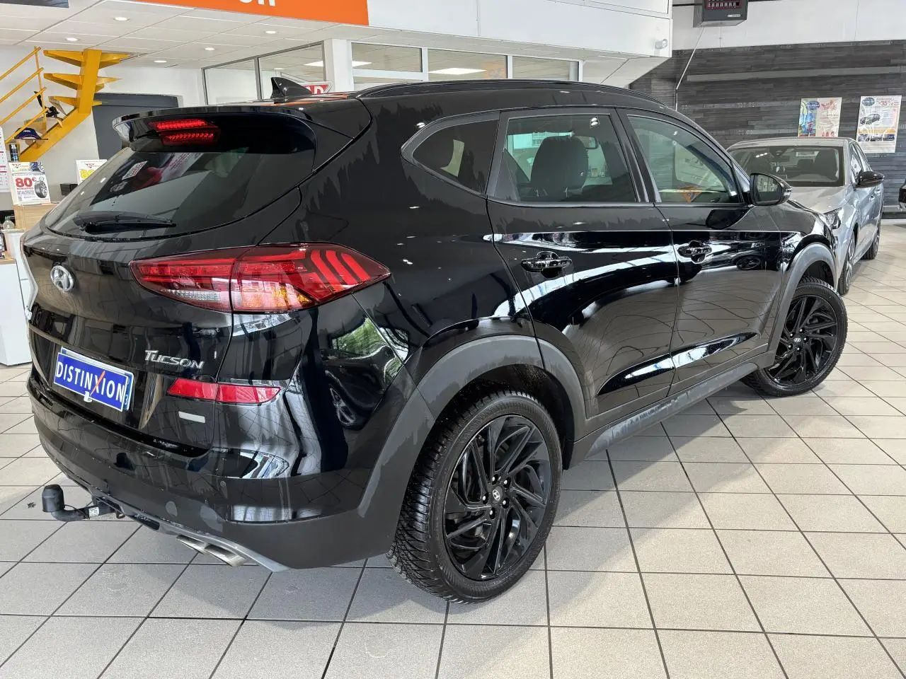 Vue 3/4 arrière droite du Hyundai Tucson noir métallisé avec jantes alliage noires et attelage en concession.