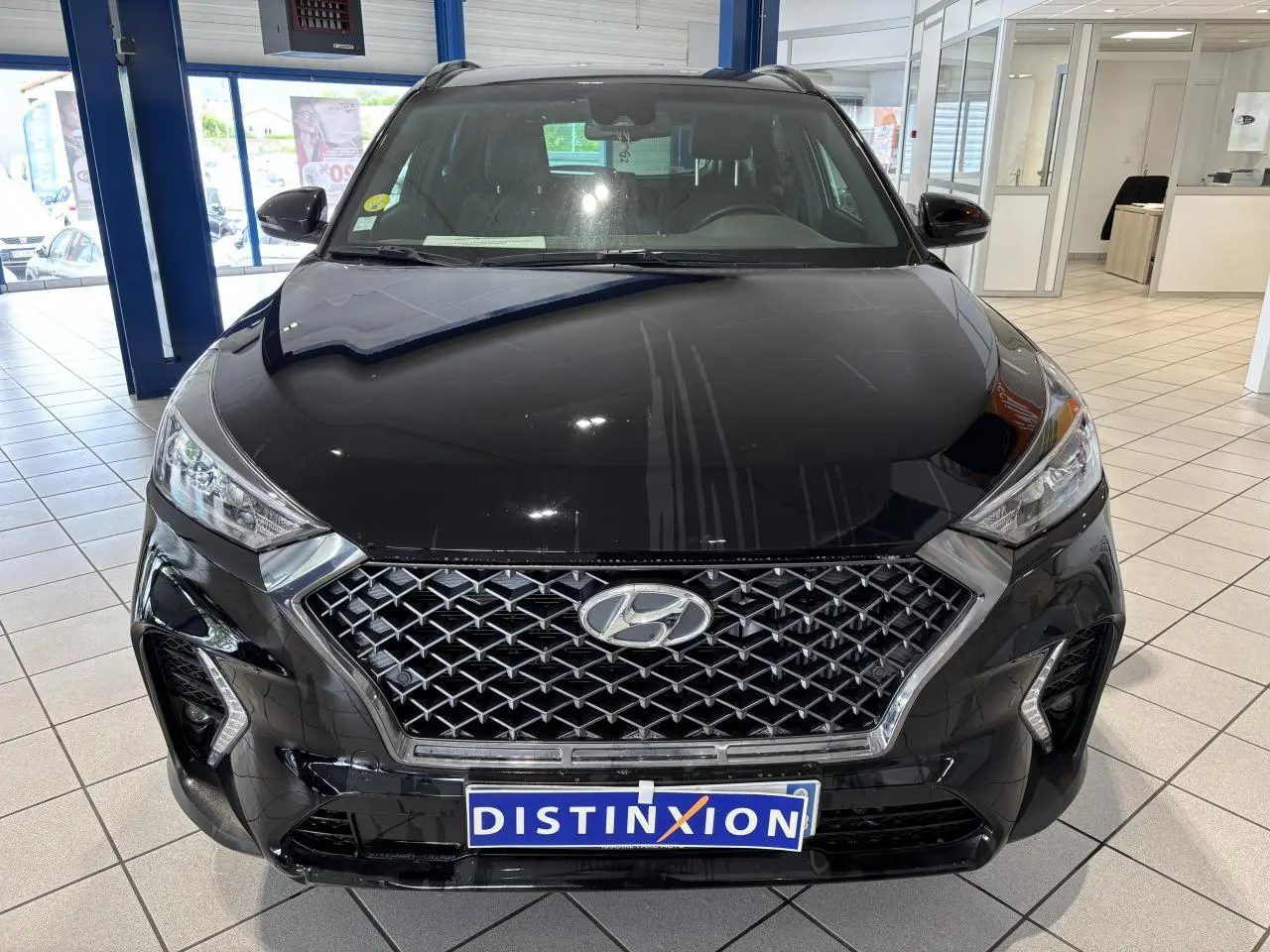 Vue avant d'un Hyundai Tucson noir avec calandre chromée et détails N Line, en intérieur showroom.