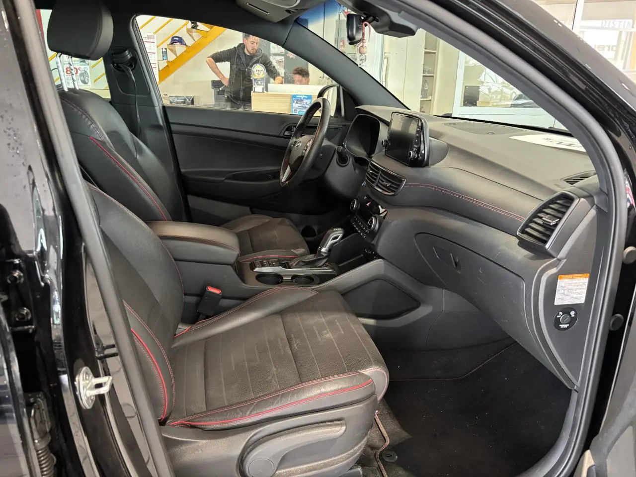Intérieur noir du Hyundai Tucson 2020 vu côté conducteur, avec surpiqûres rouges et écran tactile central.