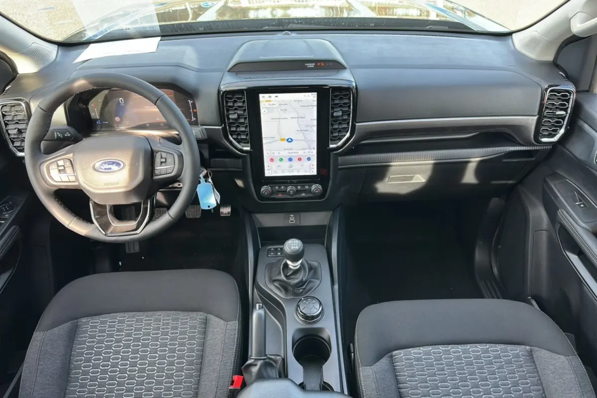 Vue intérieure avant du Ford Ranger 2026 avec tableau de bord noir, volant cuir multifonctions et écran tactile vertical.