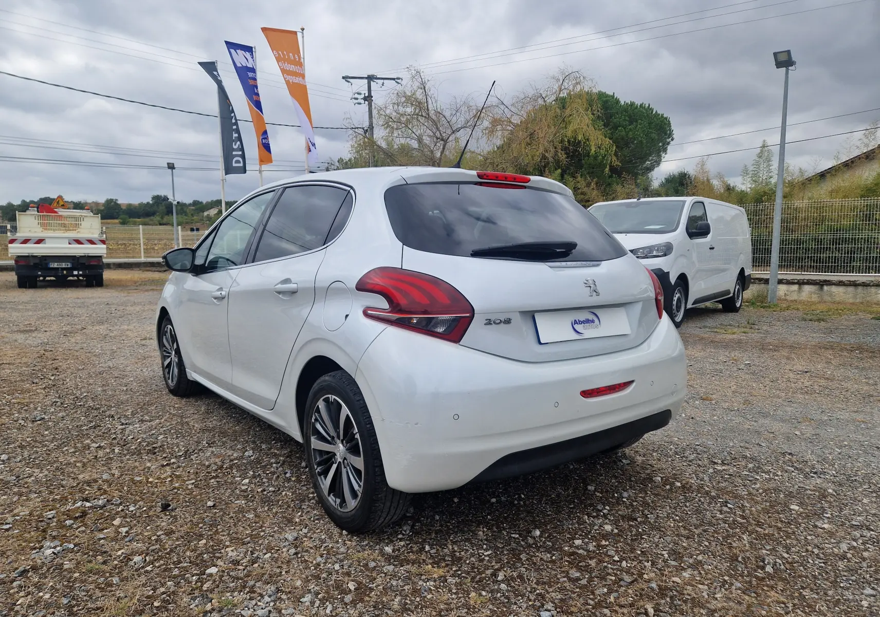 Peugeot 208 blanc nacré vue 3/4 arrière droit, avec feux arrière distinctifs et jantes bi-ton 16 pouces.