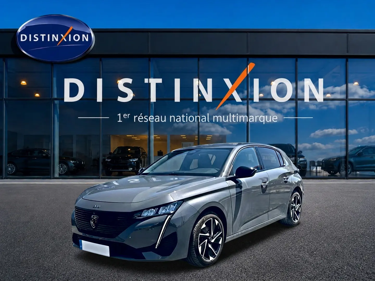 Peugeot 308 gris vue 3/4 avant droit, avec phares LED et jantes alliage distinctives, devant showroom Distinxion.