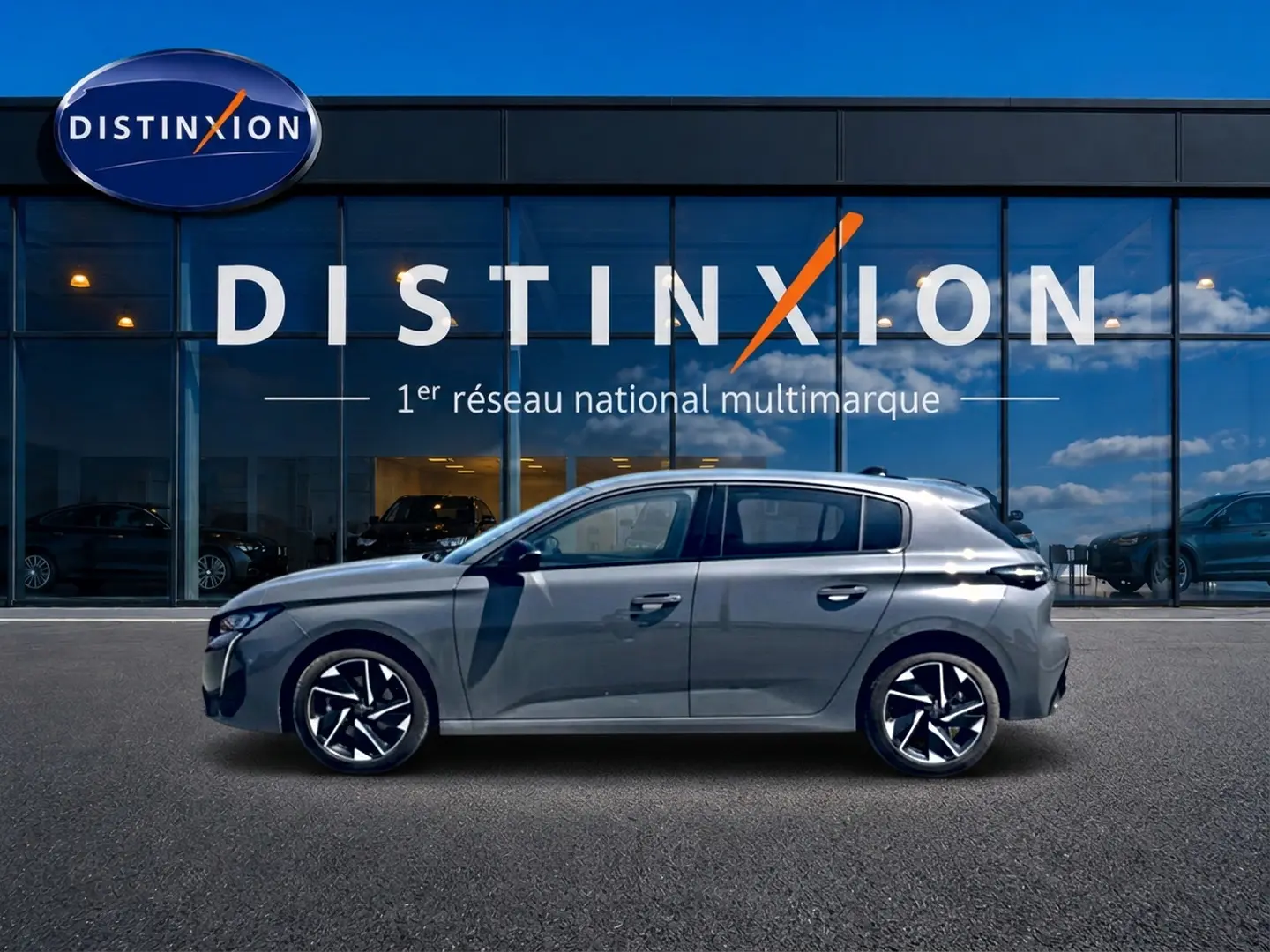 Peugeot 308 gris vue de profil côté gauche, avec jantes alliage et vitres surteintées devant un showroom Distinxion.