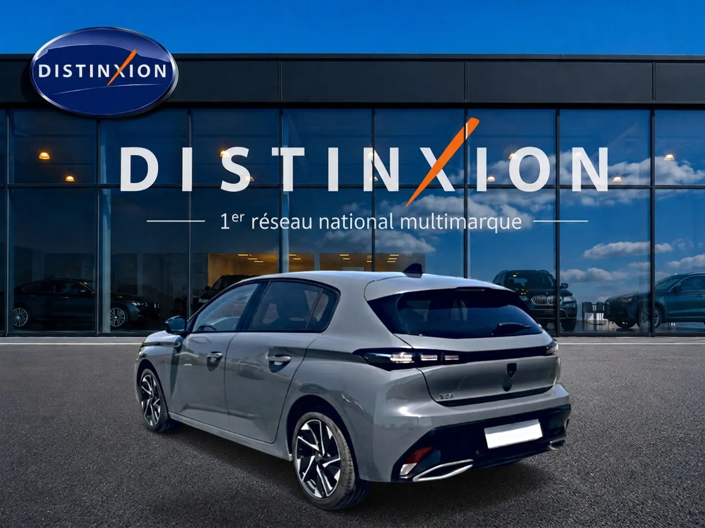 Peugeot 308 gris en 3/4 arrière droit, avec feux arrière LED et jantes alliage, devant une vitrine Distinxion.