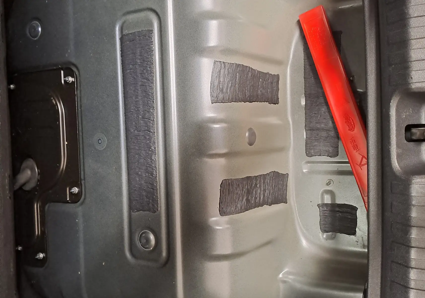 Vue rapprochée du compartiment batterie gris métallique avec un triangle de sécurité rouge dans le coffre d'une CUPRA TERRAMAR hybride.