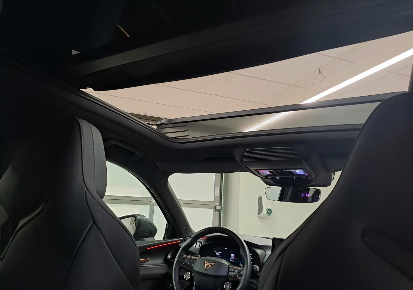 Vue intérieure avant du CUPRA TERRAMAR bleu cosmos, mettant en valeur le toit ouvrant panoramique et le volant multifonction.