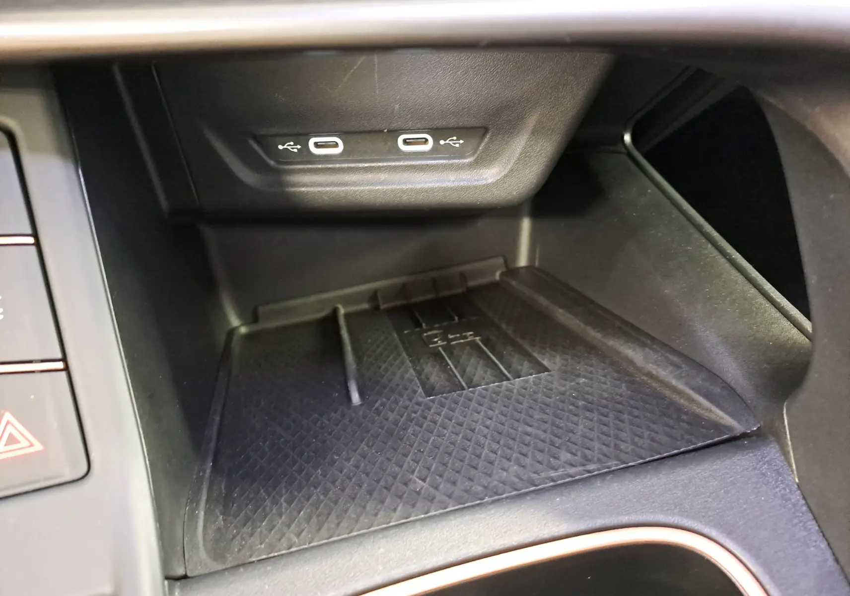 Vue rapprochée de la console centrale noire avec deux ports USB-C et un espace de recharge sans fil dans une CUPRA TERRAMAR 2025.