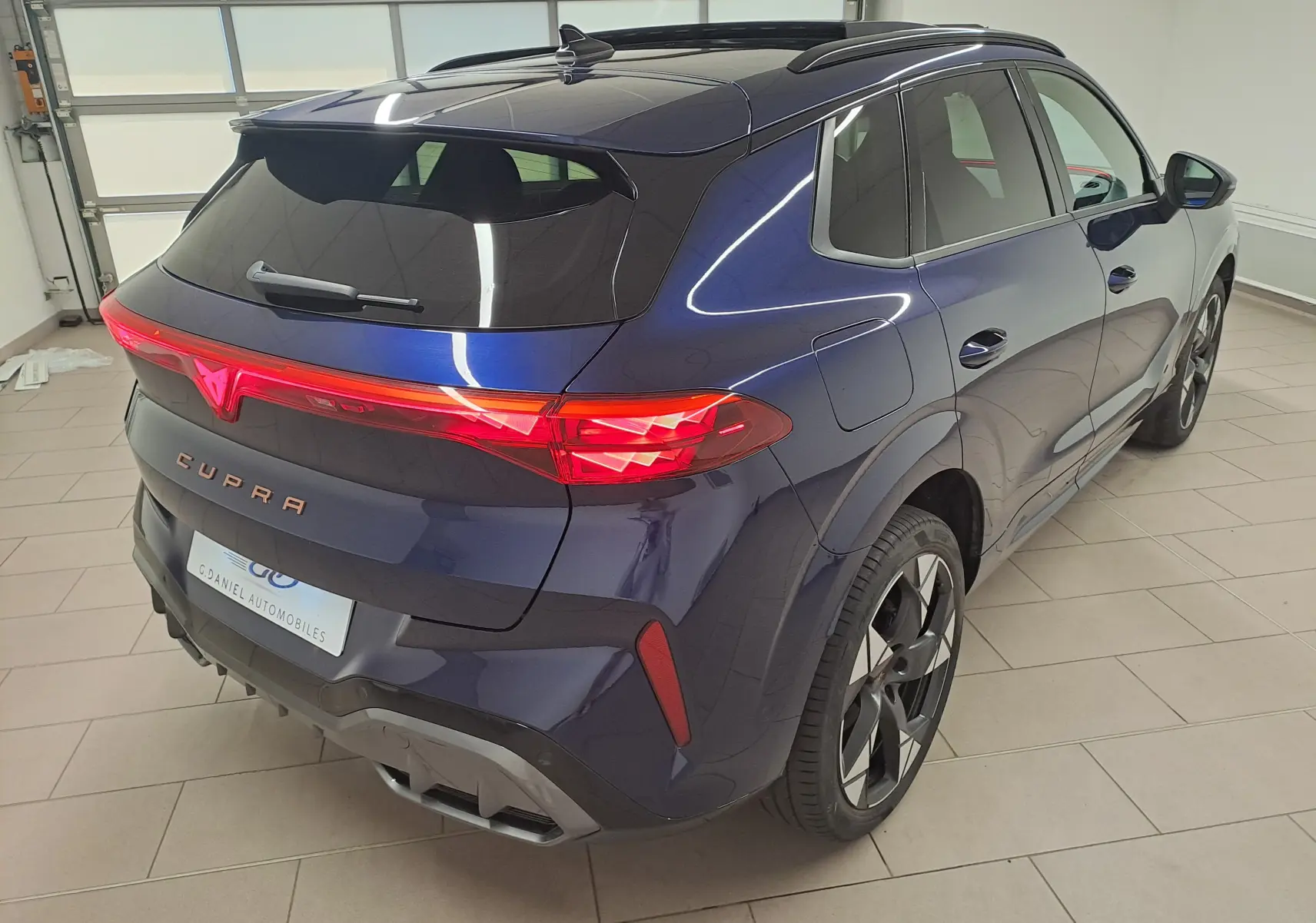 Vue 3/4 arrière droite du CUPRA TERRAMAR bleu cosmos avec feux arrière allumés et jantes 20'' Gravity usinées.