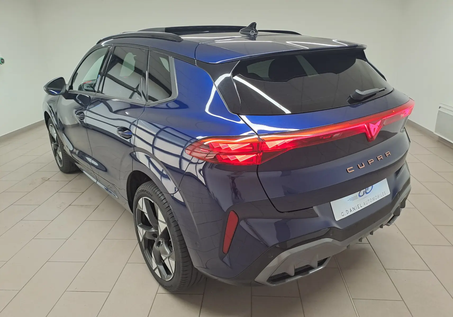 Vue 3/4 arrière droite du CUPRA TERRAMAR bleu cosmos avec feux arrière allumés et jantes 20'' Gravity usinées.