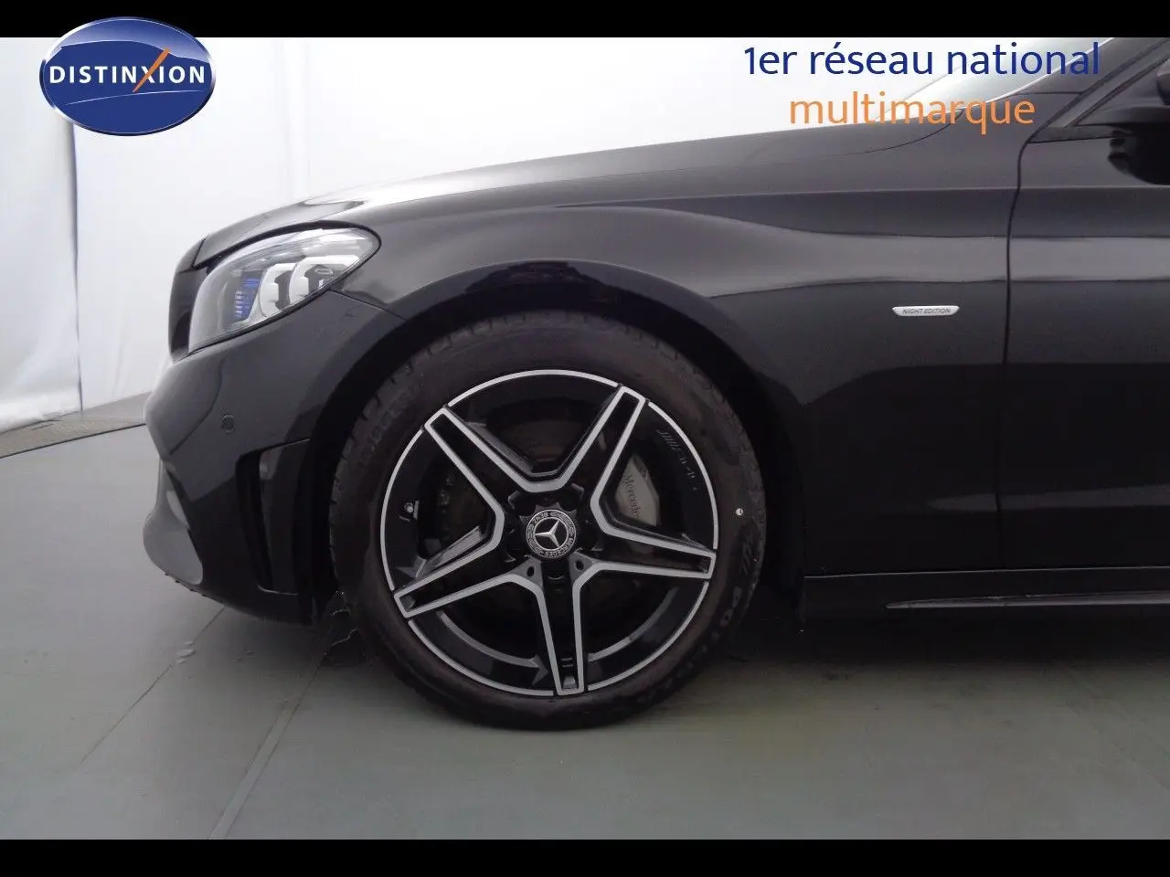 Gros plan sur la roue avant gauche et l'aile noire métallisée d'une Mercedes Classe C Break 220D AMG Line avec badge Night Edition.