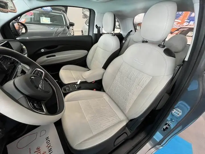 Intérieur de la FIAT 500 électrique vu côté conducteur, sièges en cuir clair avec logo embossé sur appuie-tête.