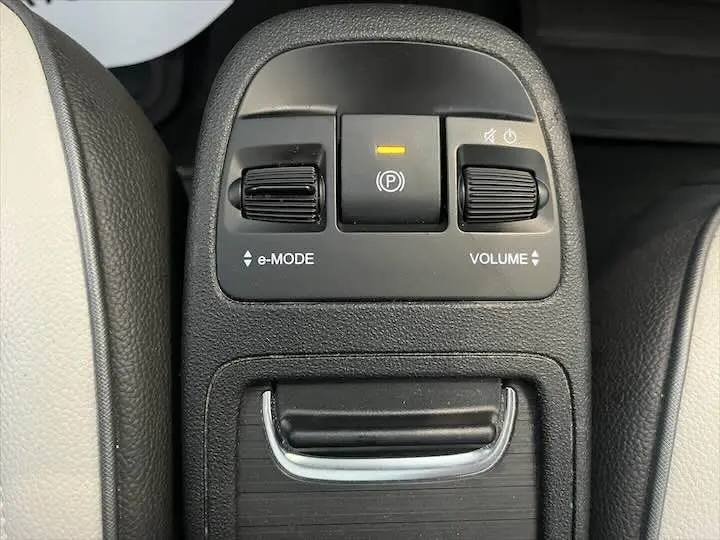 Gros plan sur la console centrale noire de la Fiat 500 électrique avec commandes e-Mode et volume visibles.