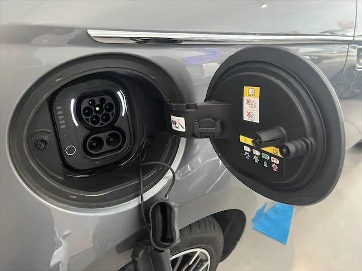Prise de recharge ouverte côté gauche d'une Fiat 500 électrique gris minéral métal, avec détails du connecteur visibles.